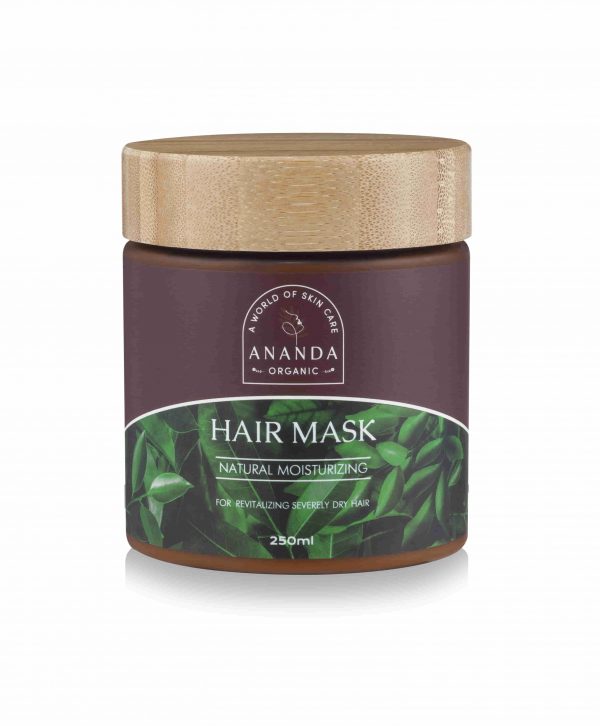 A jar of Ananda Organic Hair Mask with a wooden lid on a white background. The dark brown jar has a label reading 'Natural Moisturizing' for revitalizing severely dry hair, with a green leaf design, and contains 250ml of product